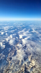 Midair, East Europe - 12. 20. 2024: Light snow on Carpatihians seen under the clouds through the jetliner window.