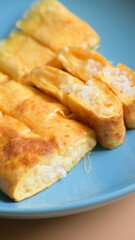 roll omelette stuffed with chesse and rice on blue plate, delicious food in the morning