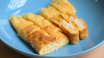 roll omelette stuffed with chesse and rice on blue plate, delicious food in the morning