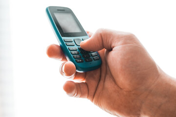 Man hold a dumbphone. An old phone. Digital minimalism concept.