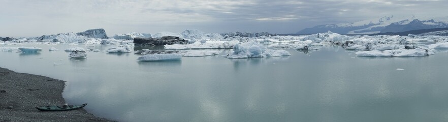 Folding kayak on the banks of the Joekulsarlon glacial lakes in front of the icebergs of the Vatnajoekull glacier, panoramic view, Iceland, Europe