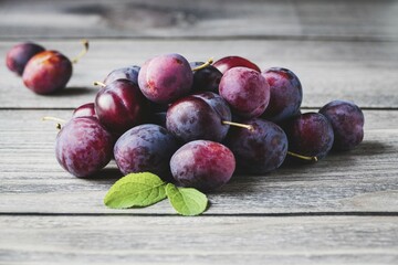 Blue plums on wooden table, harvested prune fruits in a pile