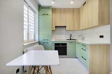 Kuchnia w nowoczesnym apartamencie w kolorze seledynowym i jasno brązowym