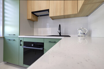 Kuchnia w nowoczesnym apartamencie w kolorze seledynowym i jasno brązowym