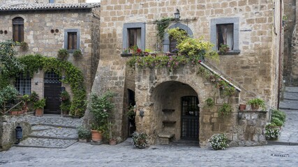 Old tufa buildings decorated with flowers in the hilltop village of Civita di Bagnoregio, Lazio, Italy, Europe
