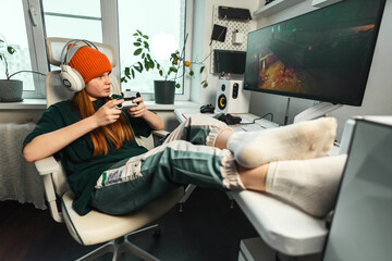 Young gamer engaged in dynamic session, combining focus and learning. Stylish workplace with computer, microphone, and buttons reflects passion for streaming, technology, and achieving personal wins. © Aboltin