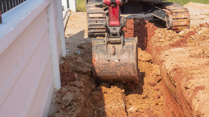 Excavator digging area for drainage pipe in construction site