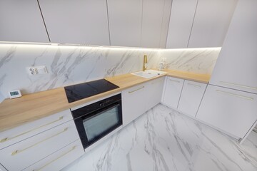 Kuchnia w nowoczesnym apartamencie w jasnych kolorach , biel,  i jasno brązowym blatem