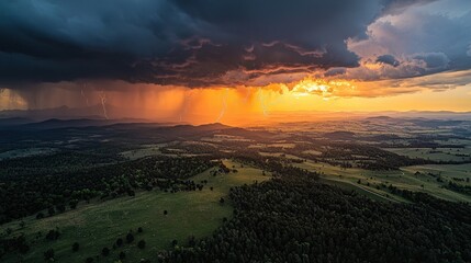 A fierce thunderstorm rolls across lush green hills as the sun sets, casting fiery orange hues in the sky. Lightning crackles and illuminates the clouds, showcasing nature's power and beauty