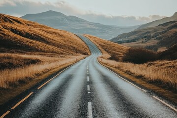 An empty road through a valley with mountains in the background