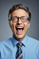 smiling man in blue shirt and tie with glasses on