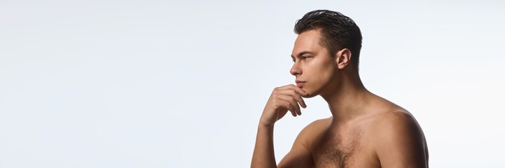 Naklejka premium Banner. Young attractive, shirtless man in thoughtful pose, shows confidence against white background with negative space to insert text. Concept of selfcare and love, natural beauty, cosmetology.