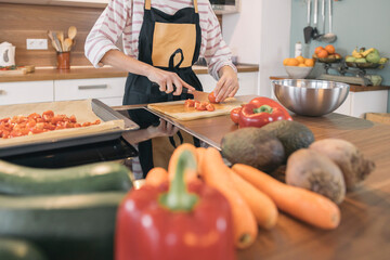 Unrecognizable girl preparing a healthy meal with fresh organic vegetables in a modern kitchen