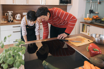 Family cooking together in modern kitchen using induction hob