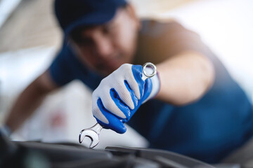 A mechanic is working on a car, using a wrench to loosen a bolt. Concept of focus and determination...
