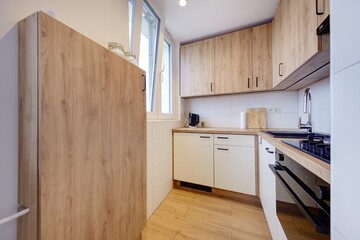 Kuchnia w nowoczesnym apartamencie w jasnych kolorach , biel,  i jasno brązowym blatem