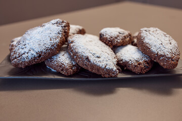 Rustic Pan dei Morti cookies with a focus on powdered sugar and dark tones, highlighting a cozy, traditional mood and artisanal texture