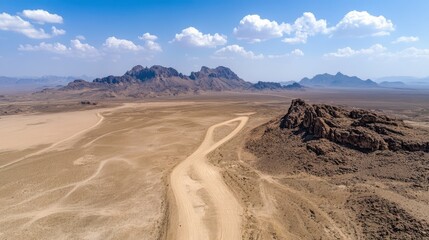 Expansive golden desert landscape with towering mountains in the distance, under a bright blue sky dotted with fluffy clouds.