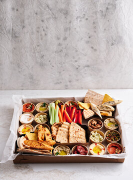 A beautifully arranged platter showcases an array of colorful dips, fresh vegetables like carrots and celery, and assorted breads. Perfect for sharing at gatherings