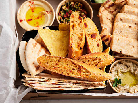 A vibrant platter features a variety of fresh flatbreads, including grilled and baked options, alongside tasty dips and sides for an enjoyable meal. Perfect for sharing with friends