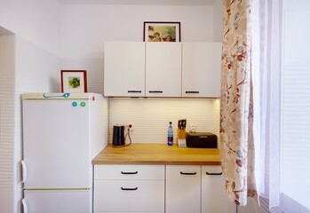 Kuchnia w apartamencie w jasnych kolorach , biel,  i jasno brązowym blatem