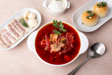 Borsch with pampushki (buns), sour cream, lard and garlic. Traditional Russian and Ukrainian soup with meat, beets, cabbage and potatoes. Close-up, selective focus.
