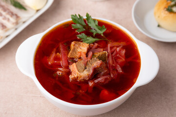 Borsch with pampushki (buns), sour cream, lard and garlic. Traditional Russian and Ukrainian soup with meat, beets, cabbage and potatoes. Close-up, selective focus.