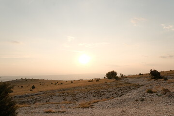 Sunset over a vast dry landscape with sparse vegetation