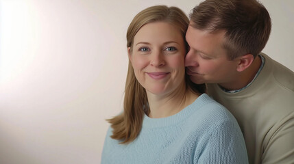 A man tenderly kisses his partner&rsquo;s cheek as she smiles with warmth. The soft lighting and neutral background enhance the feeling of love and emotional connection. Ideal for Valentine's Day themes.