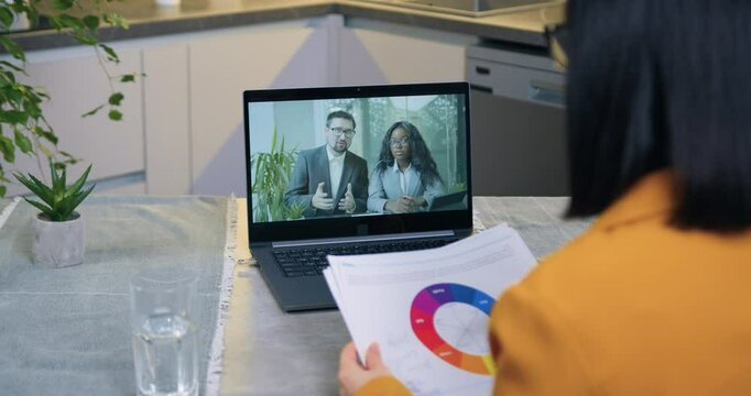 Woman which working on laptop during video briefing with her business partners and previsioning reports with diagrams