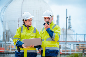 Workers collaborate on safety protocols at an industrial site during overcast weather in the...