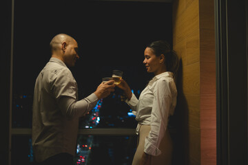 A man and woman are standing next to each other, both holding glasses of wine, celebrating your new apartament. New home concept.