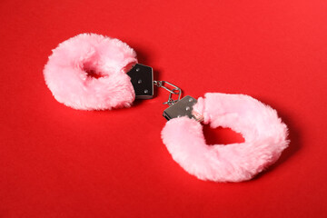 Pink fluffy handcuffs on red background. Sex toy