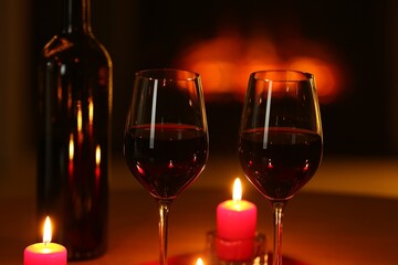 Glasses of red wine and burning candles on table, closeup. Romantic dinner