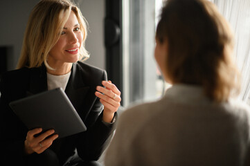 A businesswoman smiling and engaging in a face-to-face conversation with a client, listening...