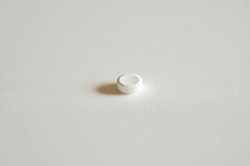 Small round white object placed on a neutral background highlights minimalist design and simplicity in modern objects