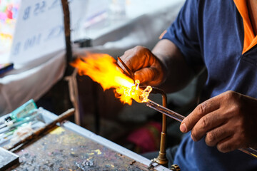 Creating glass art with hot torch and glassblowing pipe. The process of glass making, Glassblower shaping the red melted glass, A glass blower melting glass