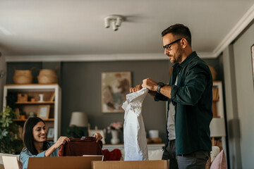 Man checking a sweater while woman packs clothes into a donation bag