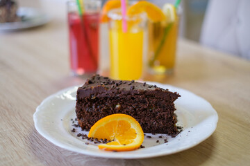 A slice of decadent chocolate cake garnished with orange sits on a plate