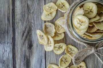 Fototapeta premium Banana Chips in a Glass Jar Light, crunchy banana chips with a golden hue, showcased in a jar tied with a rustic ribbon