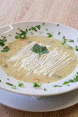 Creamy soup garnished with fresh herbs and a dollop of sauce