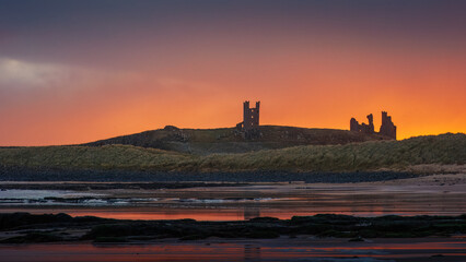 Obraz premium Sunrise over castle ruins Northumberland