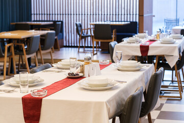 A restaurant table is set for a meal with white plates silverware and glasses