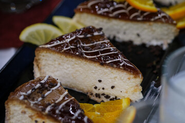 Slices of creamy cheesecake topped with chocolate drizzle and garnished with citrus
