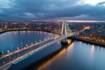 Fototapeta premium A breathtaking aerial shot of a bridge adorned with colorful lights during twilight, beautifully mirrored on the calm water, embodying urban elegance and architectural finesse.
