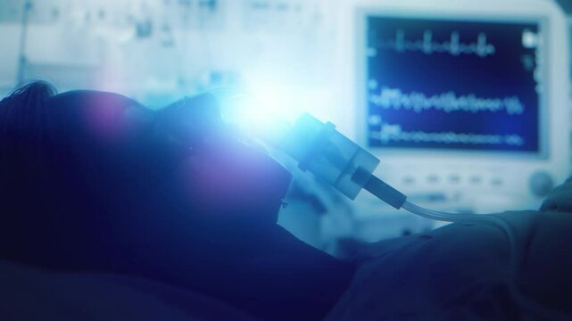 Female patient on life support with oxygen mask in hospital intensive care unit. Emergency treatment and monitoring in ICU with vital signs on screen, healthcare, medical care, and recovery treatment
