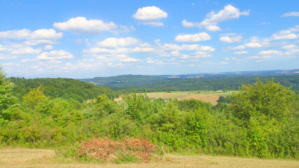 Vast countryside, green forests, rolling hills. Natural idyll, summery.