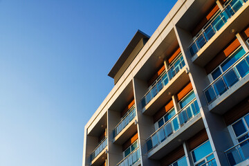 The exterior wall of a contemporary commercial style building has aluminum metal composite panels and glass windows. The futuristic building has engineered diagonal cladding steel frame panels.