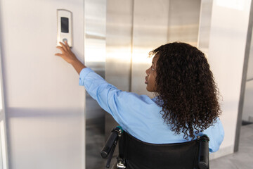 Businesswoman in wheelchair in corporate office using touch panel to operate the lift