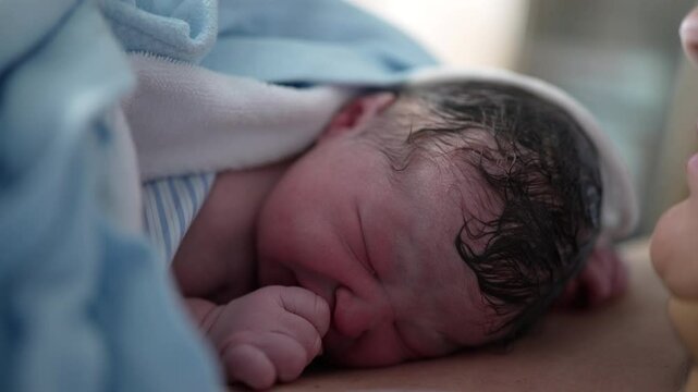 Close-up of newborn baby right after birth resting on mother's chest emphasizing skin to skin contact. authentic real life birth moment, first minutes of life of infant